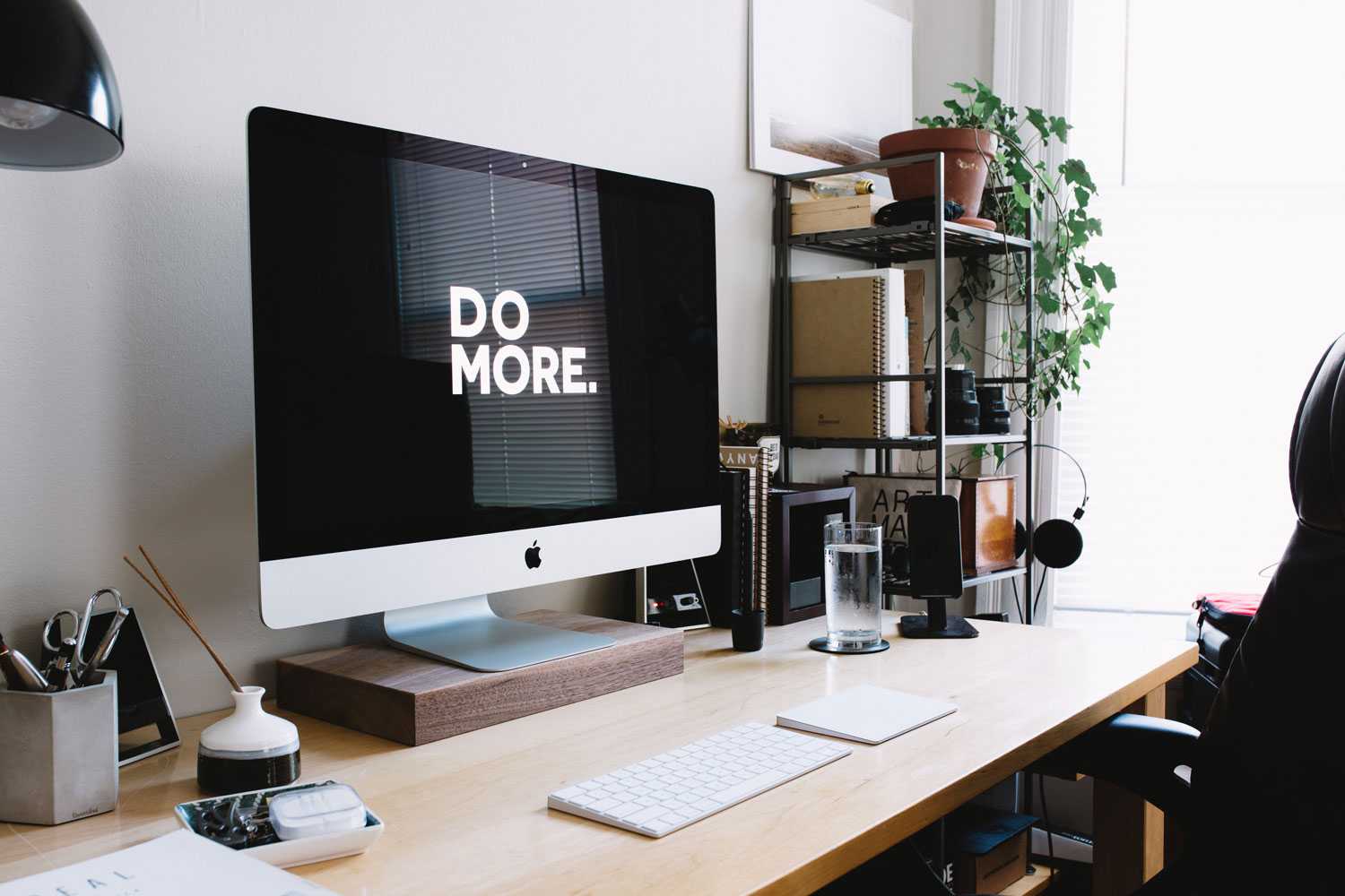 Do More With Less Tidy desktop setup with and iMAC that has a wallpaper prompting you to do more
